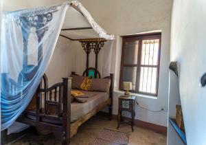 a bedroom with a canopy bed and a window at Ella's Swahili Villa - Restored 1840s Heritage Home in Bagamoyo