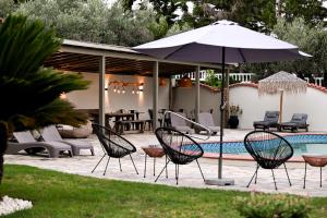 a patio with chairs and an umbrella next to a pool at Aggelos Grand in Koukounaries +29 photos