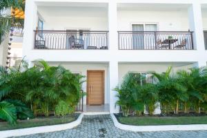 a white building with a door and palm trees at Residencial Esprit Caribbean in Bayahibe