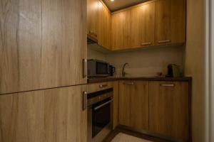 a small kitchen with wooden cabinets and a microwave at Apartments Salim in Sarajevo