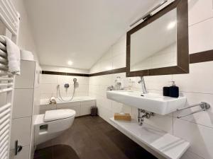 a white bathroom with a sink and a toilet at Boutique Hotel Alpenhof in Sankt Martin am Tennengebirge +143 photos