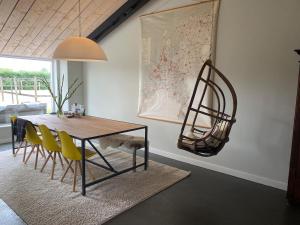 a dining room with a table and yellow chairs at Slapen bij Uppruna in Chaam