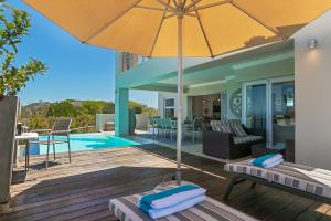 a patio with an umbrella and a pool at SL9 - Pezula Double Storey Luxury in Knysna