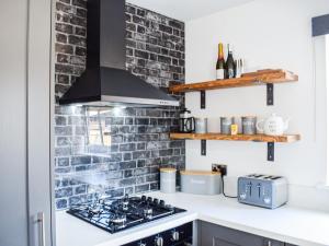 a kitchen with a stove and a brick wall at Rubys Cottage in Crieff +14 photos
