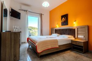 a bedroom with a bed with an orange wall at Rizos Bay Sarakiniko in Sarakiniko