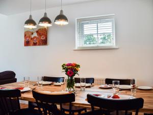 a dining room table with chairs and a vase of flowers at Rubys Cottage in Crieff