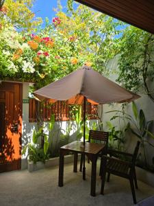 a table with an umbrella and a chair and a bench at Dhonfalhu Dhigurah in Dhigurah