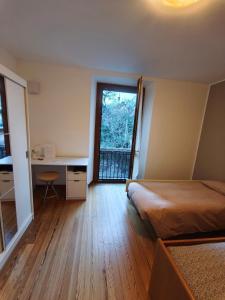 a bedroom with a bed and a desk and a window at In Centro in Domodossola