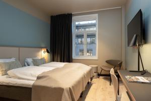 a hotel room with a bed and a desk and a window at Comfort Hotel Park in Trondheim