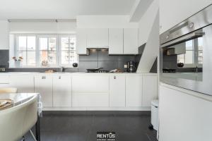 a white kitchen with white cabinets and a table at Maison Beluga - spacious apartment in Westende in Middelkerke