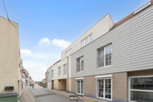 a building on a street with a person riding a bike at Maison Beluga - spacious apartment in Westende in Middelkerke