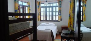 a bedroom with two bunk beds and two windows at Jacque's Beachside Hostel in Progreso