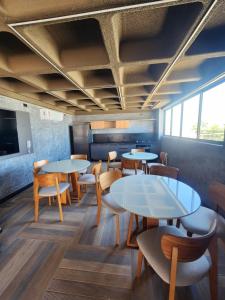 a dining room with tables and chairs and windows at Apartamento Edifíco Prestige in Marechal Deodoro