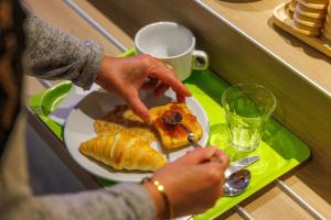a person is eating a plate of breakfast food at Hotel ibis budget Aix Les Bains - Grésy in Grésy-sur-Aix