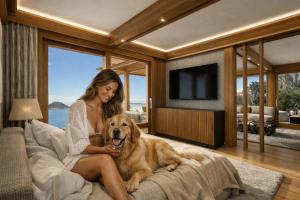 a woman sitting on a bed with a dog at Baba Residences in Alassio