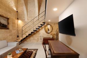 a living room with a couch and a tv on a wall at Nelsonhaus -Boutique Guesthouse in Cospicua +29 photos