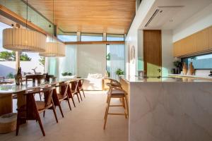 a kitchen with a long bar with wooden chairs at OASIS Luxury Private Villa in Ban Phru Champa
