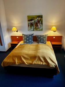 a bedroom with a large bed with two lamps at Restaurant Rebea in Sulzburg