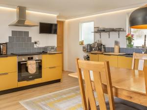 a kitchen with yellow cabinets and a table and chairs at Old Quay in Newlyn