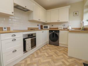 a kitchen with white cabinets and a dishwasher at Wardenlea in Preston