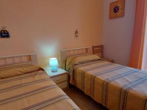two beds in a bedroom with a lamp on a night stand at 023 e 024 Tulipano di SalentoInVacanzaCOM in Torre Pali