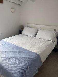 a bed with white sheets and pillows in a bedroom at Foretop Cottage, Staithes in Staithes