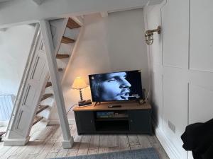 a living room with a tv and a staircase at Foretop Cottage, Staithes in Staithes