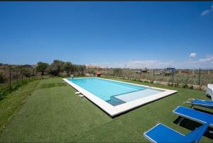 a swimming pool in a yard with blue lawn chairs at Villa Marzamemi in Marzamemi