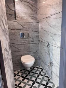 a bathroom with a toilet and a black and white floor at Rajal Dormitory in Indore