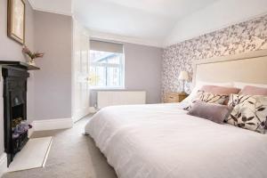 a bedroom with a large white bed and a fireplace at Bronafon in Rhyl