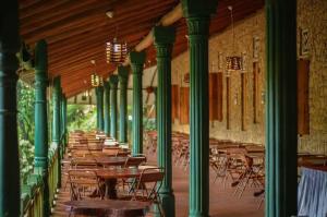 a row of tables and chairs in a room with green columns at Terico resort in Belihuloya