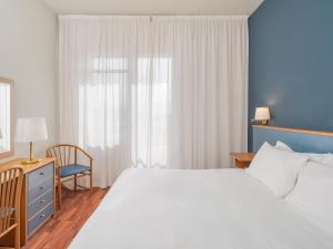 un dormitorio con una cama blanca grande y una silla en B&B HOTEL Riviera Celle Ligure, en Celle Ligure 25 fotos más