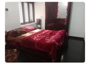 a bedroom with a bed with a red blanket on it at Dream Home in Irimbranallūr