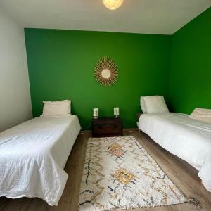 two beds in a room with a green wall at Ostal del Koï in Rabastens +20 photos