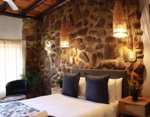 a bedroom with a stone wall with a bed at Silverlakes Farm Hotel in Pretoria
