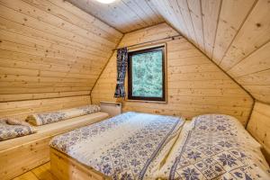 two beds in a log cabin bedroom with a window at Pod Horou a za Potokom, Podbanské in Pribylina