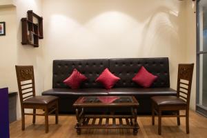 a black couch with red pillows and a table at Hostells - Backpacker Hostel near Pune Station in Pune