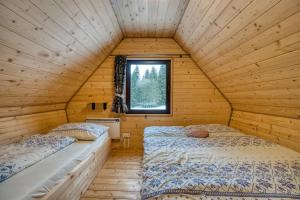 two beds in a wooden room with a window at Pod Horou a za Potokom, Podbanské in Pribylina