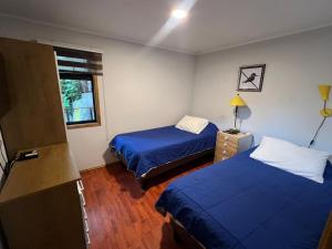 a bedroom with two beds and a window at Hospedaje El Roble, Puerto Varas in Puerto Varas