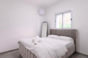 a bedroom with a large bed with white sheets and a window at אירוח תמר in Qiryat Shemona