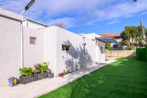 a white house with a green lawn at אירוח תמר in Qiryat Shemona