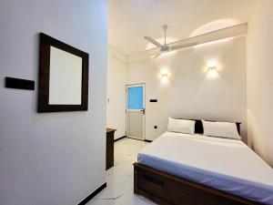 a white bedroom with a bed and a mirror at Cloud View Family Villa in Kandy