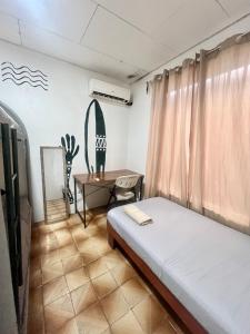 a bedroom with a bed and a table and a surfboard on the wall at Casa bohio surf in Jacó