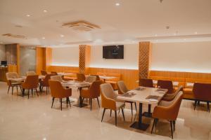 a restaurant with tables and chairs and a flat screen tv at Hotel Siddharth Grand in Varanasi