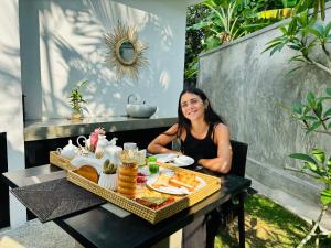 a woman sitting at a table with a tray of food at RV Regency 19 Hotel in Tangalle