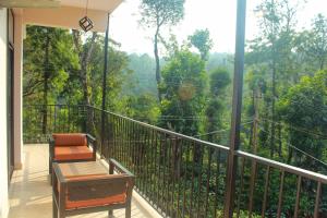 a balcony with a chair and a view of the forest at Coorg Homes in Madikeri +11 photos
