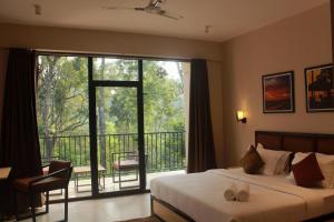 a bedroom with a bed and a balcony with a large window at Coorg Homes in Madikeri