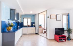 a kitchen with blue walls and white cabinets and a tv at Cielo Mar in S'Illot +20 photos