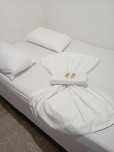 ein weißes Bett mit weißen Laken und weißen Kissen in der Unterkunft Hotel La Séptima in Neiva