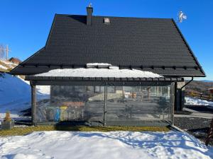 a glass building with a black roof in the snow at Domek w Chmurach II in Kicznia +42 photos